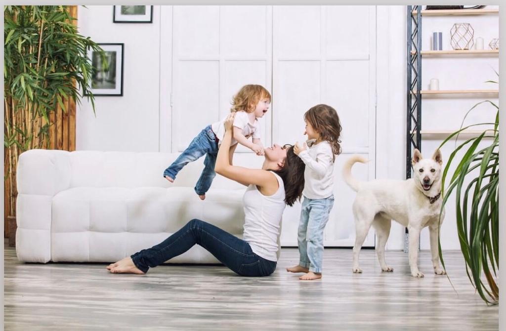vrouw zittend op de vloer met 2 kinderen en een hond